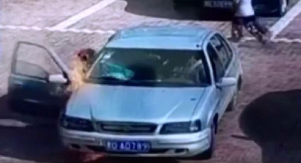 一中国男子试图吹灭一辆燃烧的轿车