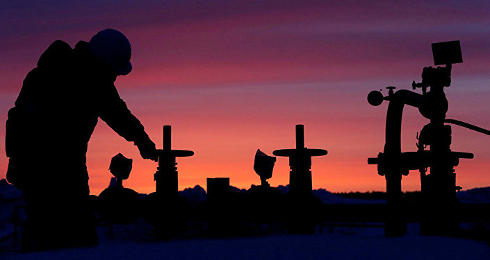 A worker checks the valve of an oil pipe at an oil field