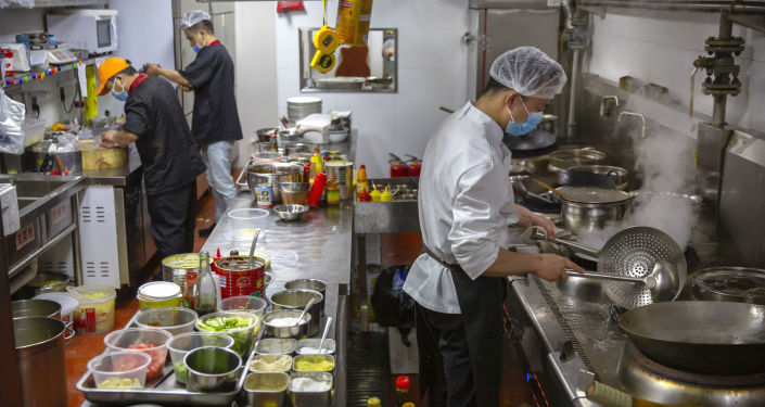 staff members wear face masks to protect against the spread of the new coronavirus as they work in the kitchen at Little Yunnan restaurant in Beijing